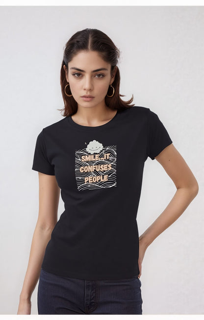 Woman wearing a black t-shirt with a graphic design featuring a smiling cloud and the text "Smile. It Confuses People" over a wavy line background.
