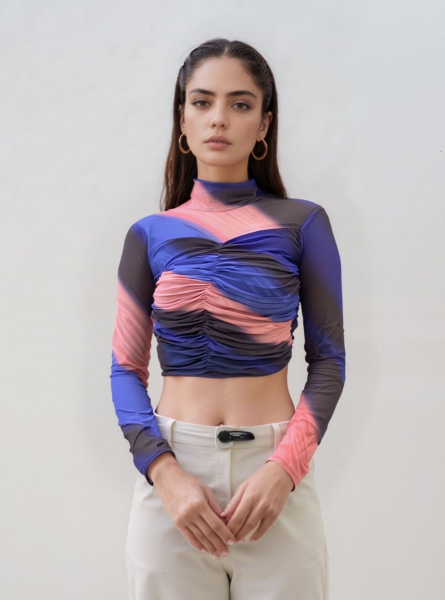 Woman wearing a colorful long-sleeve top against a plain background