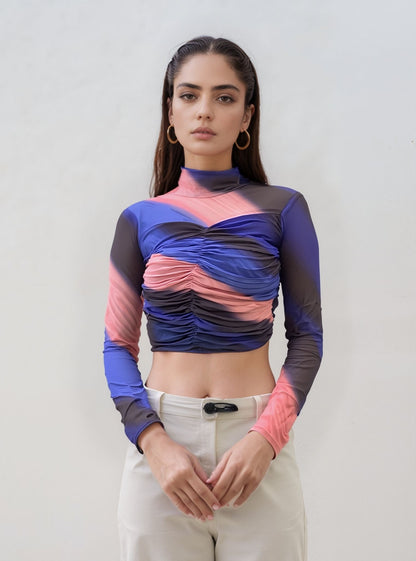 Woman wearing a colorful long-sleeve top against a plain background