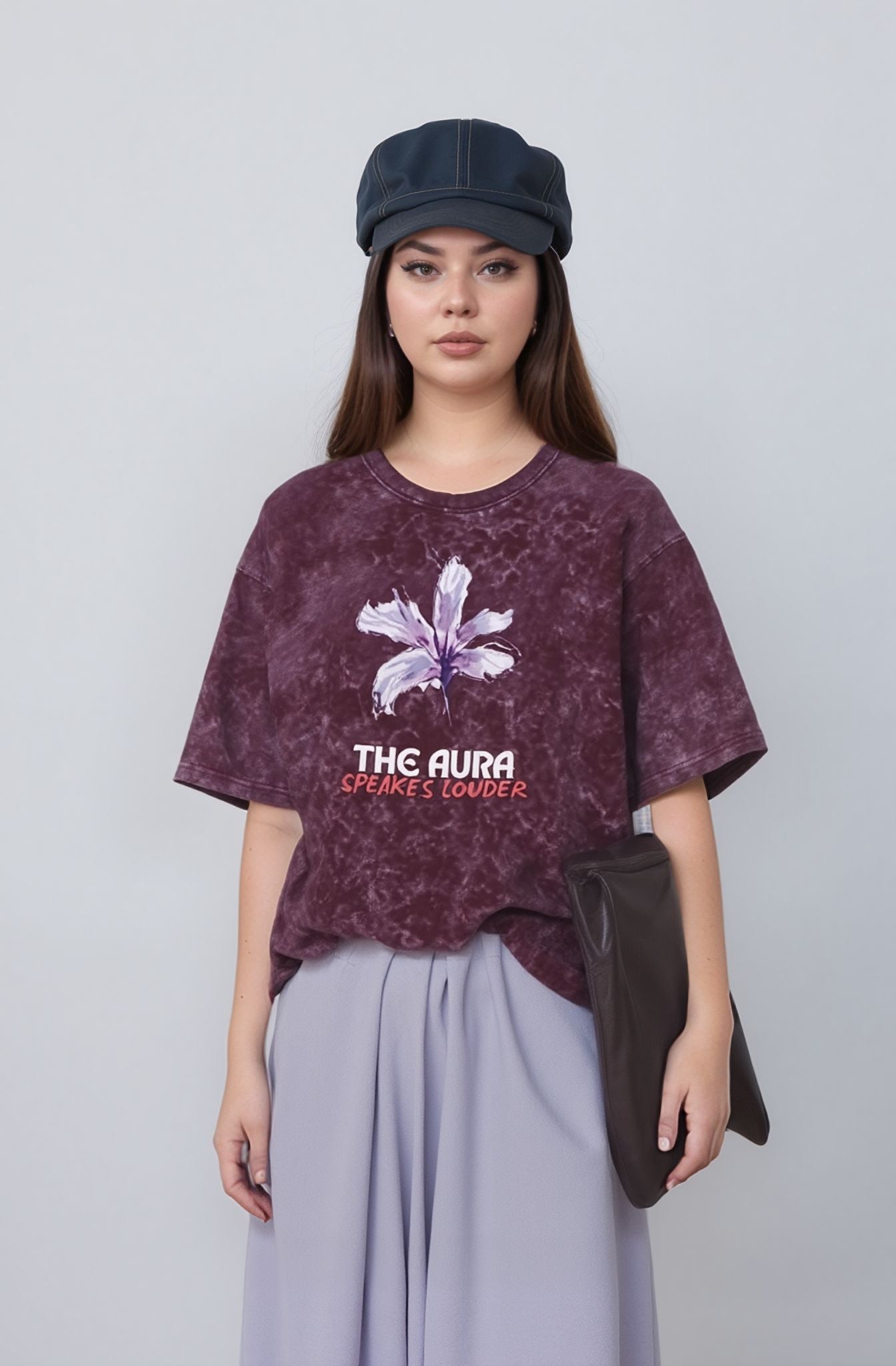 Woman wearing a maroon t-shirt with a graphic design and text, standing against a plain background