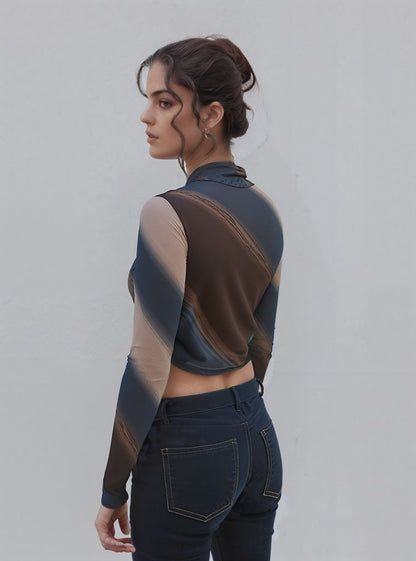 Rear view of a woman showcasing a ruched mesh crop top with gradient brown, blue, and nude tones. She is wearing dark denim jeans with visible stitching and has her hair tied back in a bun.