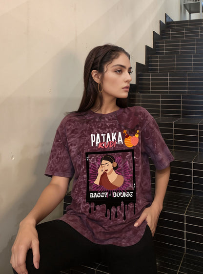Person wearing a maroon t-shirt with 'Pataka' branding sitting on a staircase.