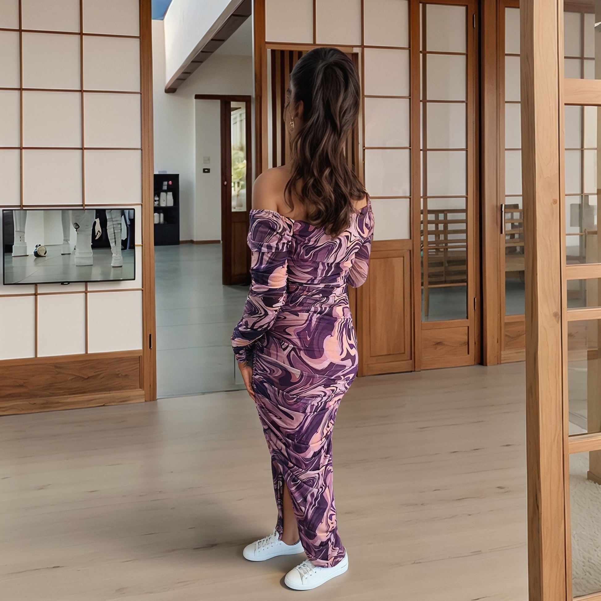 Back view of model wearing off-shoulder purple marble swirl bodycon dress with high slit, styled with wavy half-up hairstyle and heels