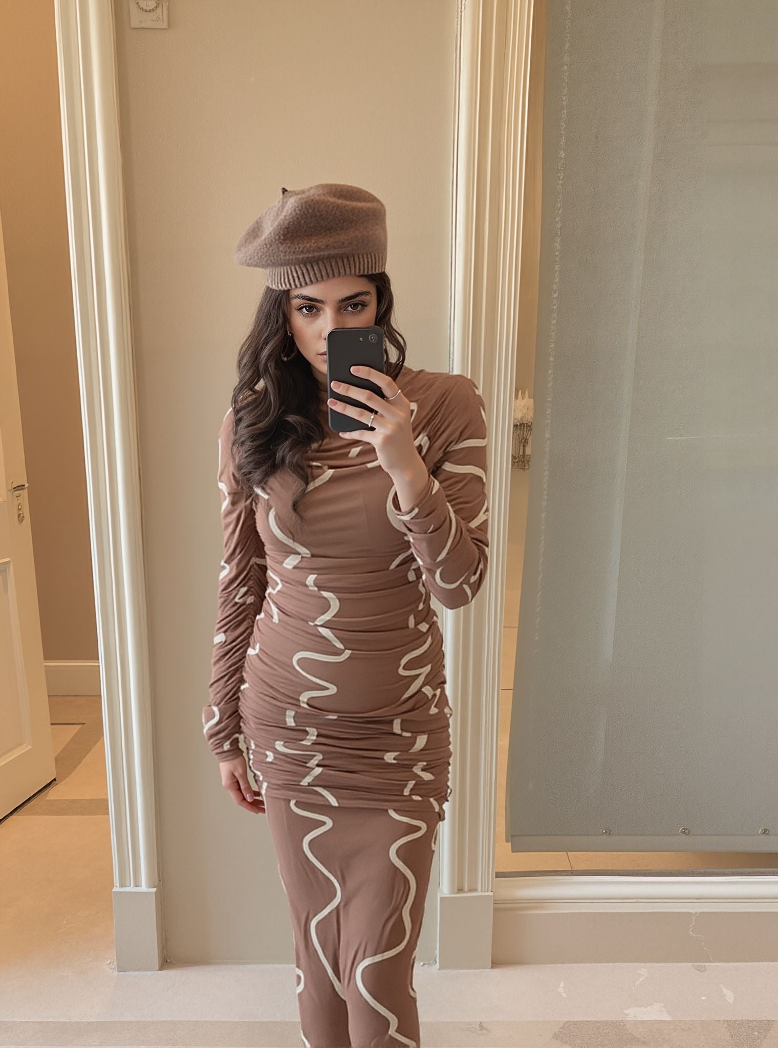 Mirror selfie of woman wearing swirl print ruched bodycon dress, styled with a brown beret.