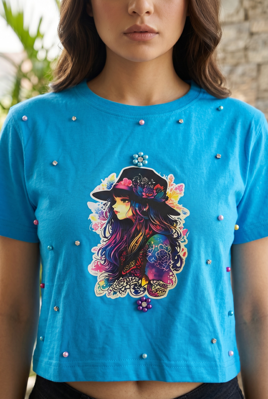 Close-up of blue graphic crop top featuring artistic print with pearl and rhinestone embellishments.