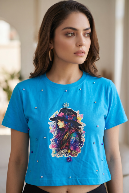 Three-quarter view of women’s blue embellished graphic crop top with pearl and rhinestone detailing.
