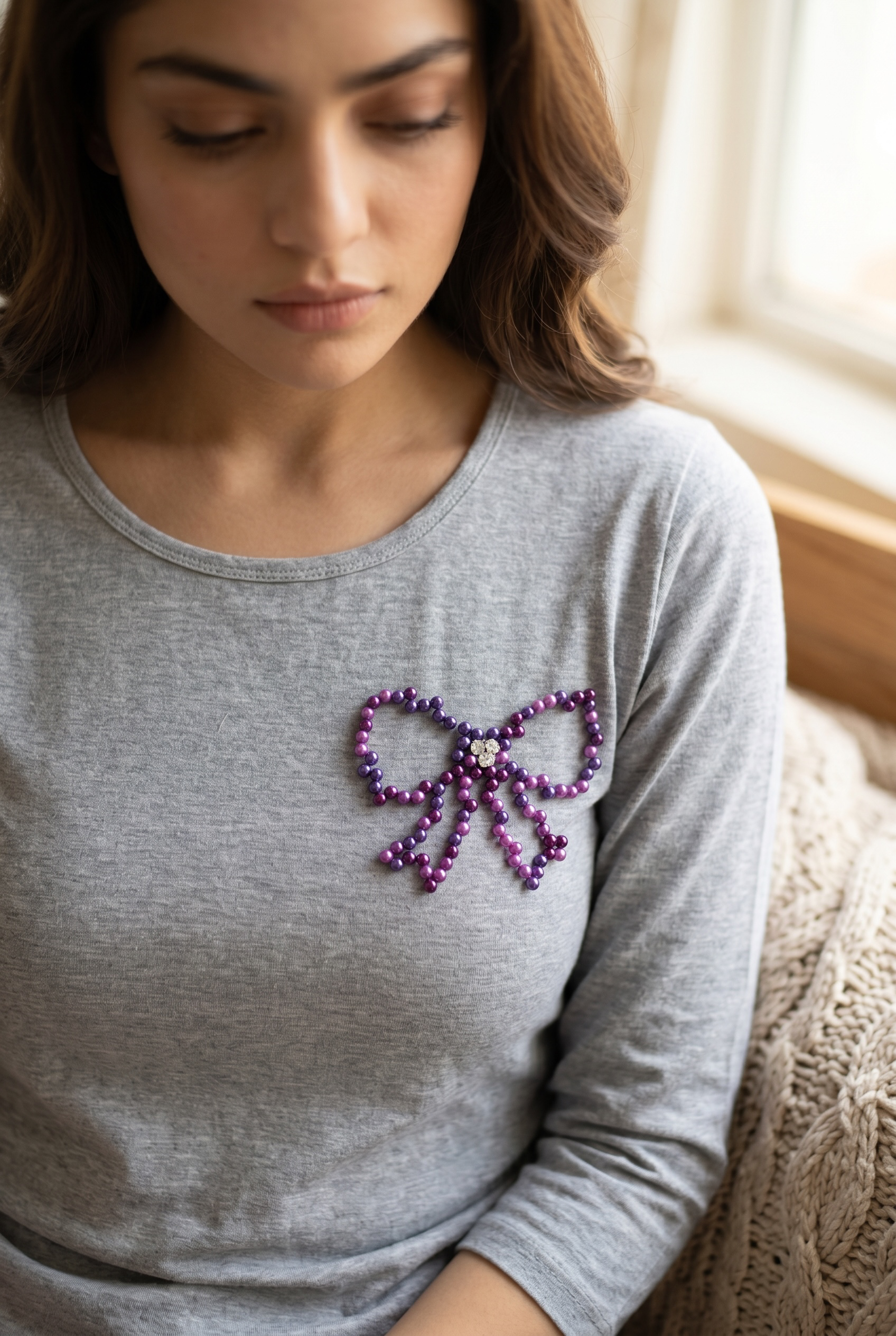 Side angle of grey cotton full sleeve T-shirt featuring a handcrafted pearl bow motif.
