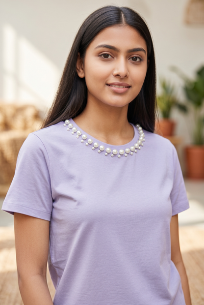 Woman wearing a lavender cotton crop top with a hand-embellished pearl neckline.
