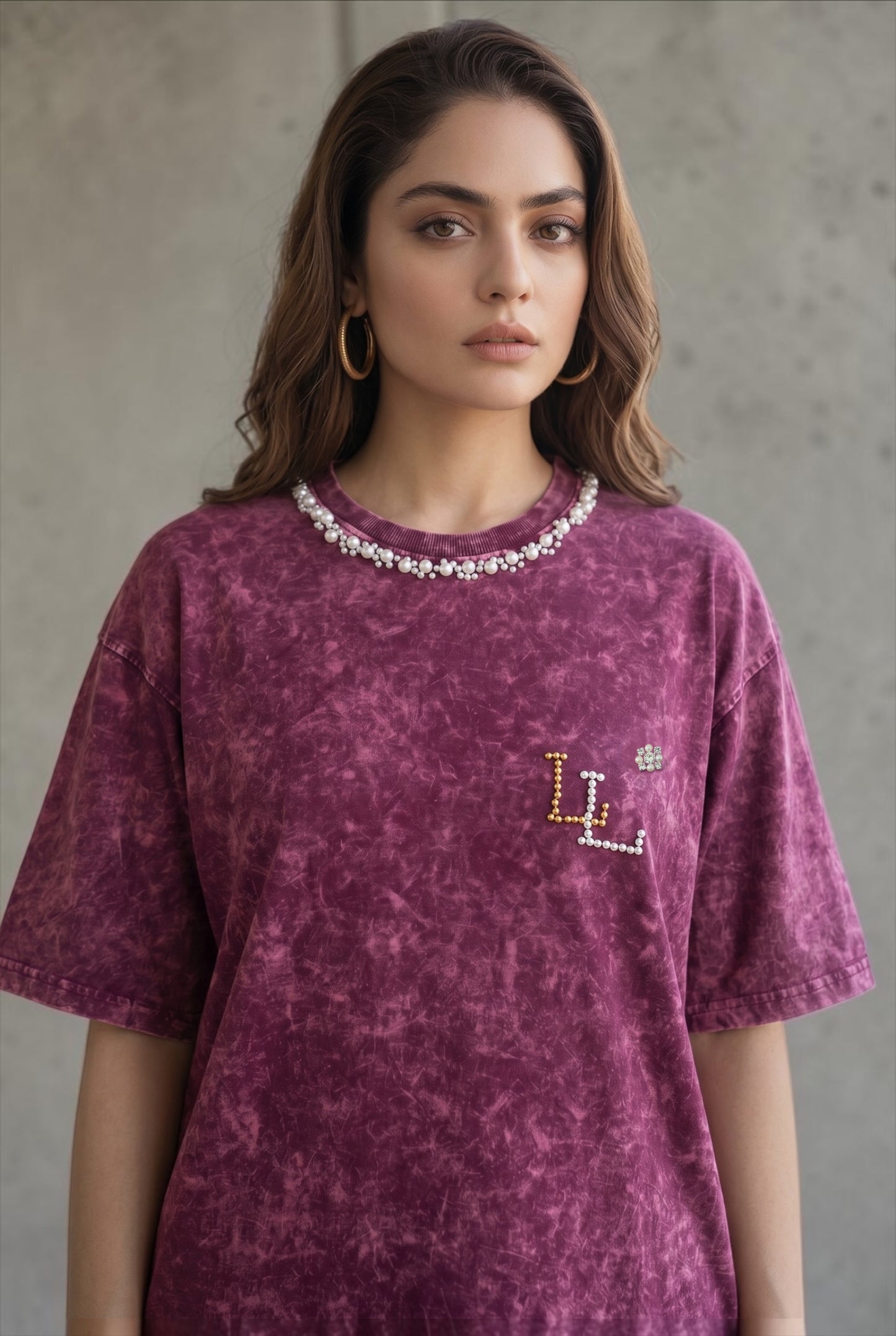 Woman wearing a maroon acid wash oversized T-shirt with hand-embellished pearl neckline and pearl logo detail.
