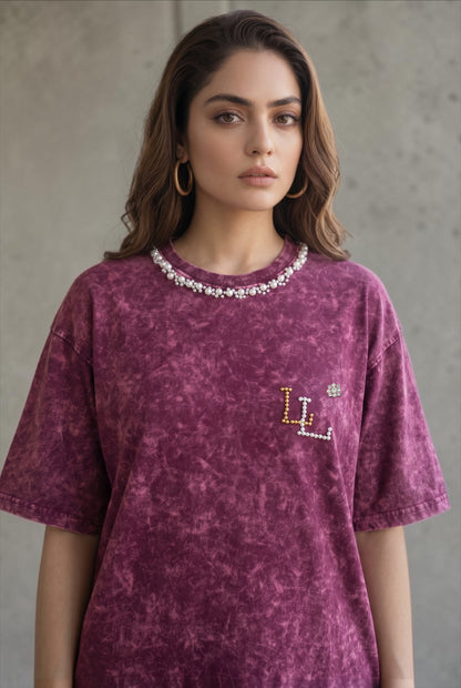 Woman wearing a maroon acid wash oversized T-shirt with hand-embellished pearl neckline and pearl logo detail.
