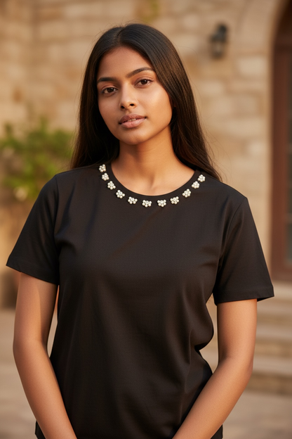 Close-up of hand-embellished pearl floral neckline on women’s black cotton T-shirt
